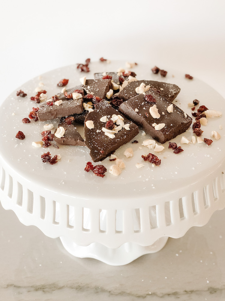 chocolate bark on a cakestand with cashews and dried cranberries